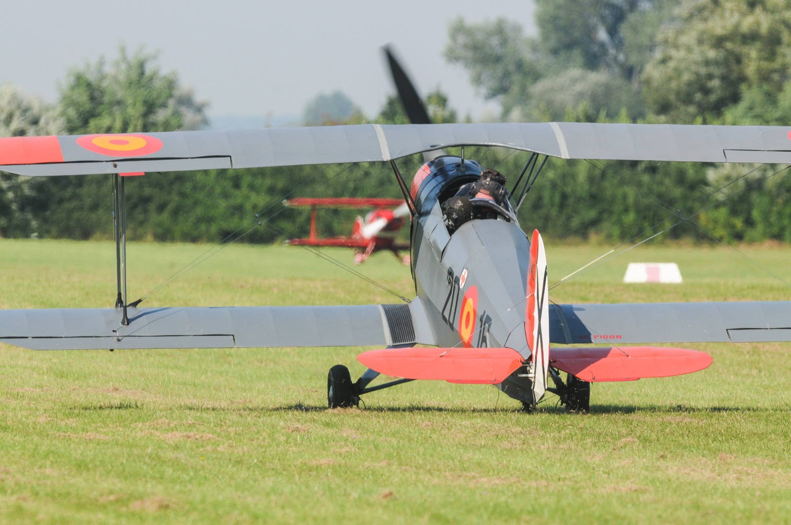 Historisches Flugzeug auf dem Flugfeld mit Pilot daneben
